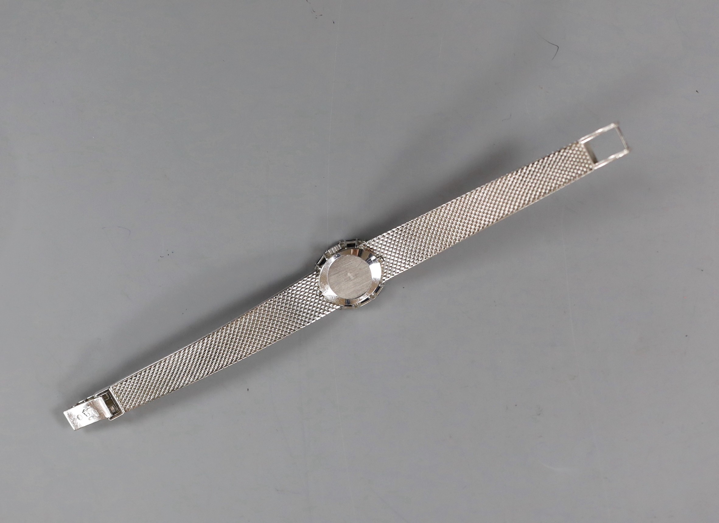 A lady's French 750 white metal Omega manual wind oval wrist watch, with sapphire and diamond set bezel, on integral Omega 750 white metal bracelet, overall 17.7cm, gross weight 52.5 grams, no box or papers.